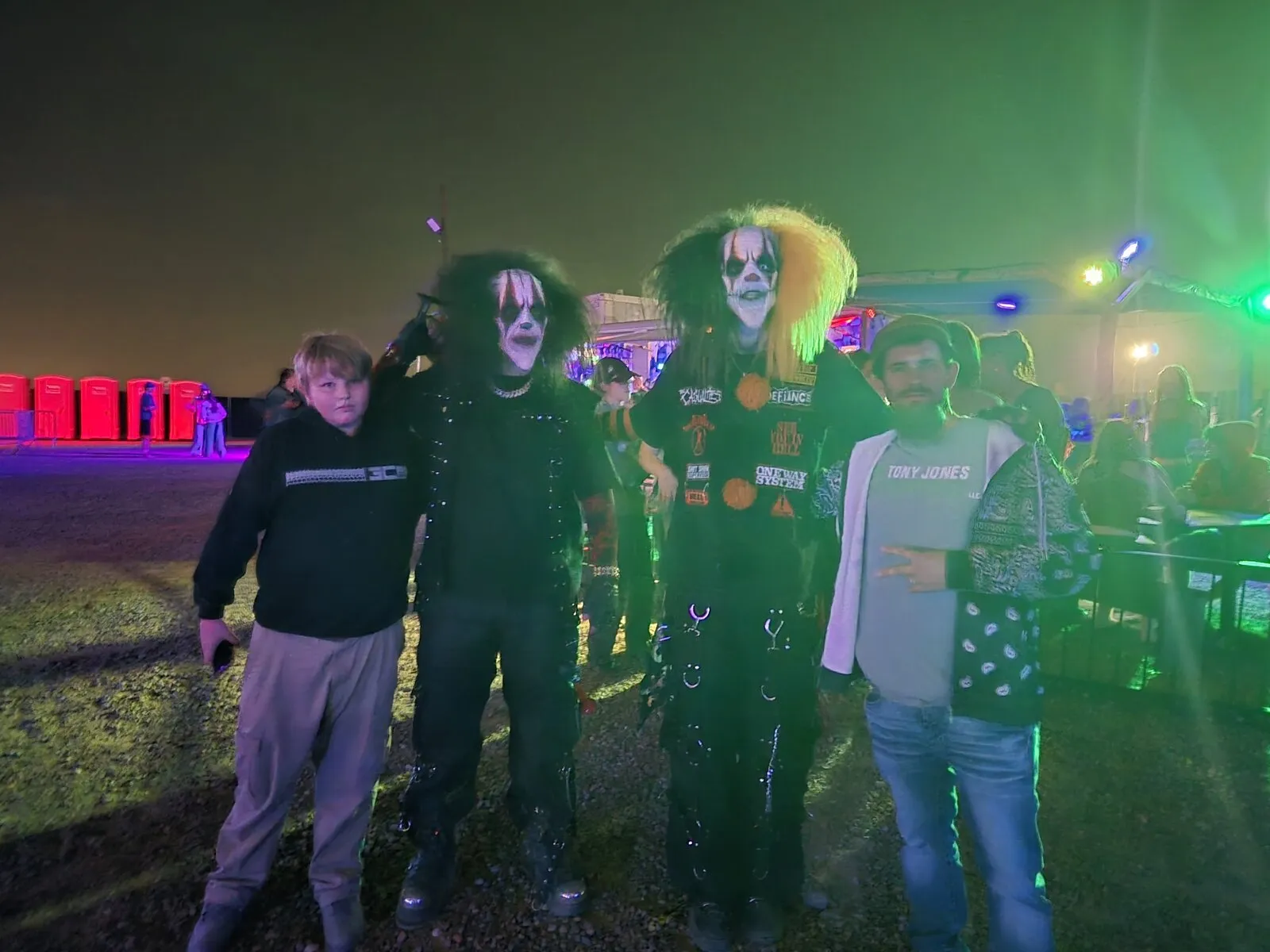 A family group stands between two face-painted clown characters on the scaregrounds