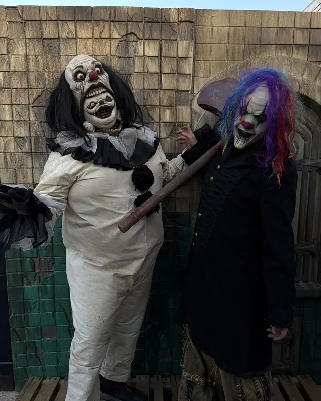 Two clown characters, one in a rainbow wig, holding a mallet on the Scarizona Scaregrounds set