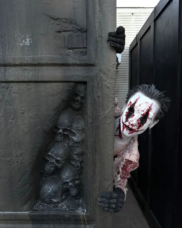 A bloodied clown character leaning out from behind a skull-carved wall at Scarizona Scaregrounds