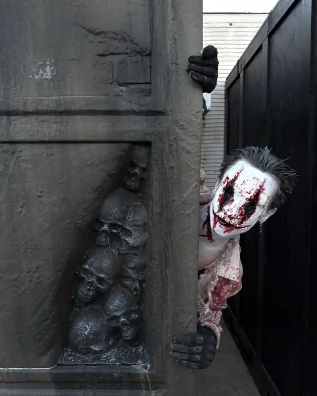 A bloodied clown character leaning out from behind a skull-carved wall at Scarizona Scaregrounds