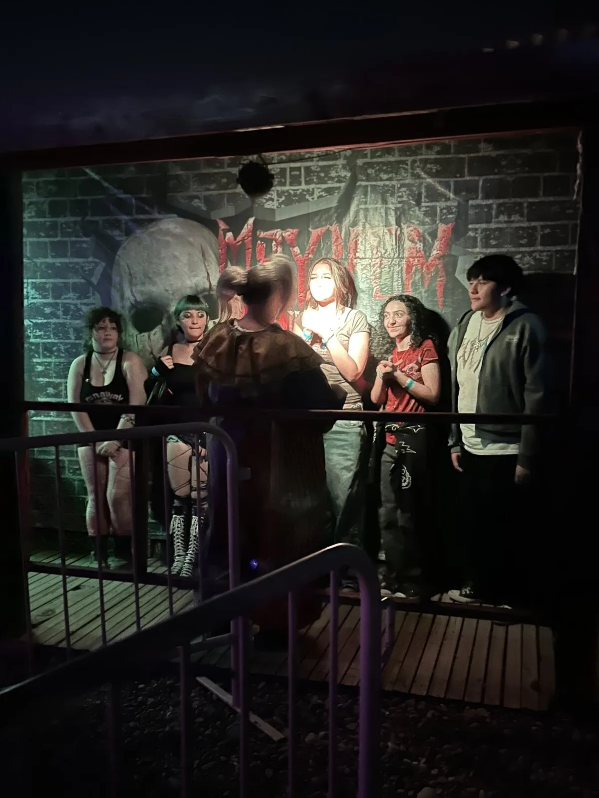 A group of guests waits at the railing outside a haunted house entrance