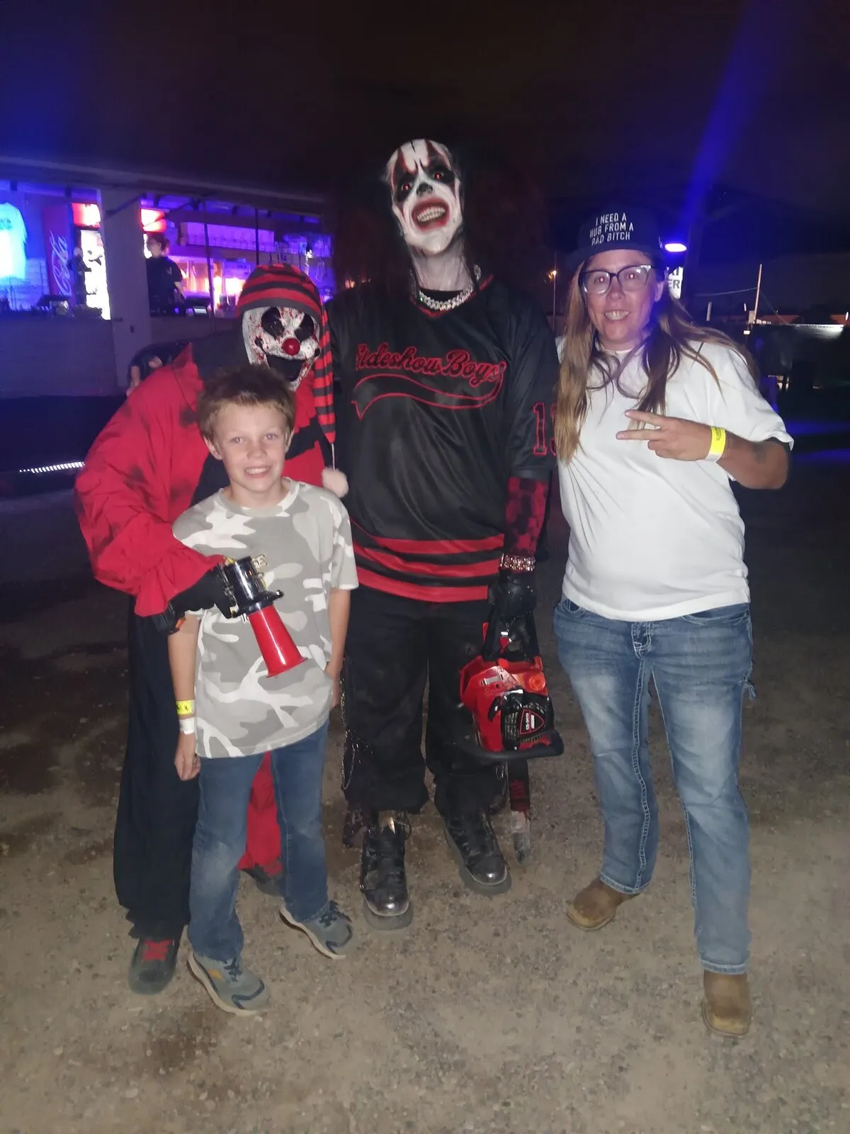 A guest and a boy stand with two clown characters, one gripping a prop chainsaw